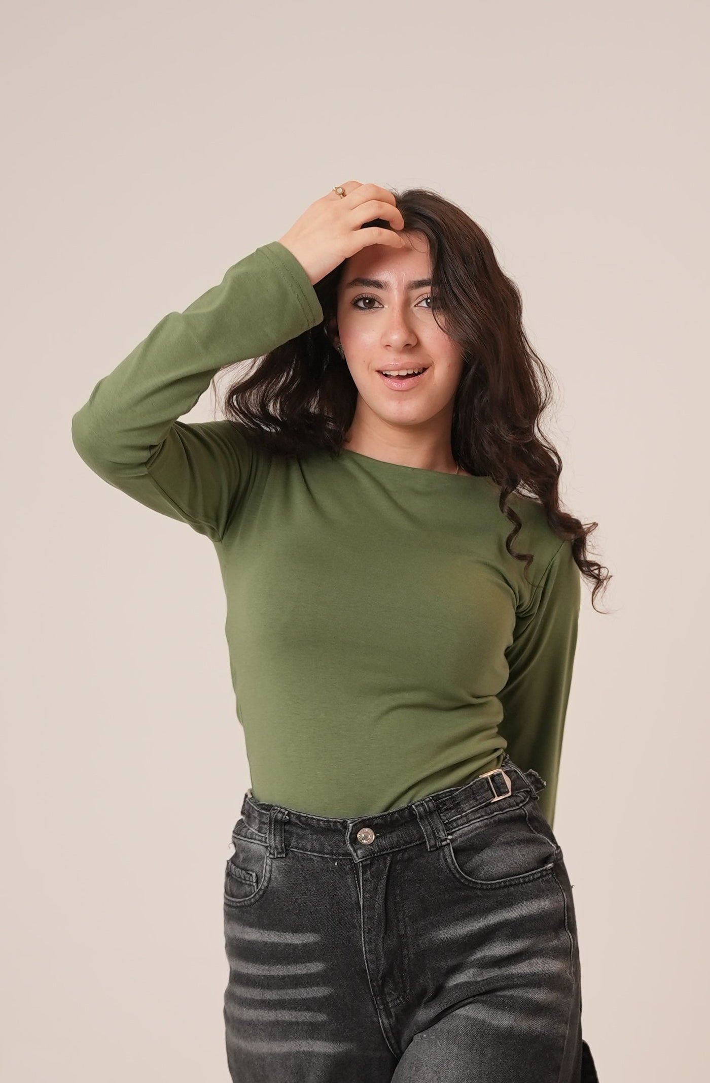 Person wearing a green hoodie and dark pants lying on a light-colored floor.